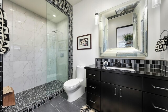 bathroom with a tile shower, backsplash, tile patterned flooring, vanity, and toilet