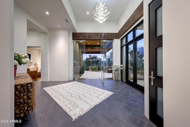 foyer entrance with dark tile patterned floors, a towering ceiling, and a chandelier