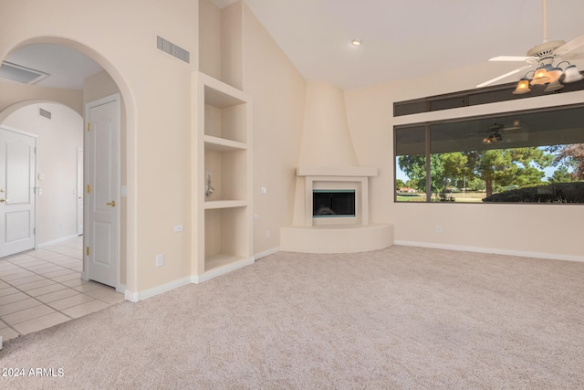 unfurnished living room with a large fireplace, built in features, light tile patterned floors, and ceiling fan