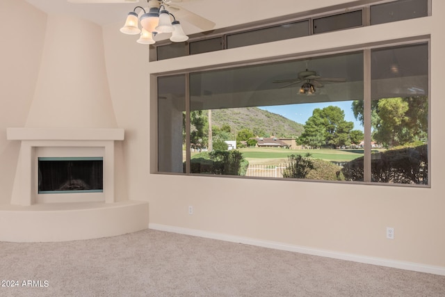 unfurnished living room featuring carpet, a mountain view, a large fireplace, and ceiling fan