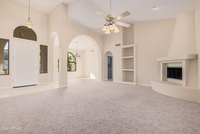 unfurnished living room featuring light colored carpet, high vaulted ceiling, built in features, and ceiling fan