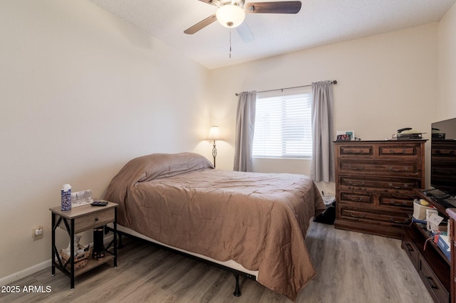 bedroom with light wood finished floors, a ceiling fan, and baseboards