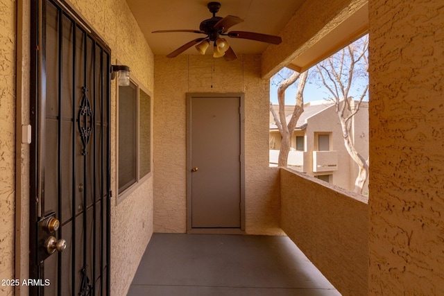 doorway to property featuring a balcony, ceiling fan, and stucco siding