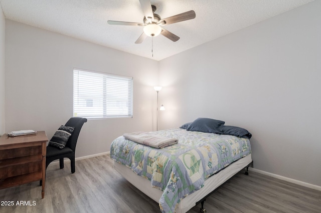 bedroom featuring a textured ceiling, wood finished floors, and baseboards