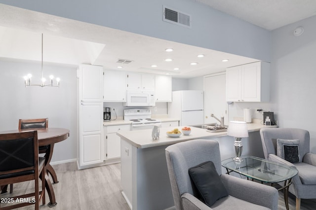 kitchen with white appliances, visible vents, white cabinets, light countertops, and pendant lighting