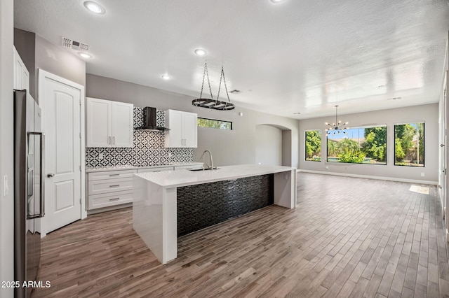 422 E Kaibab Pl, Chandler, AZ 85249 - kitchen featuring wall chimney range hood, wood finished floors, open floor plan, backsplash, and light countertops
