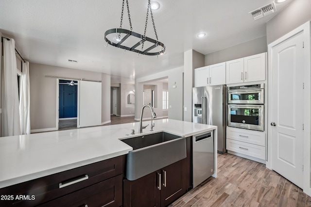 422 E Kaibab Pl, Chandler, AZ 85249 - kitchen featuring appliances with stainless steel finishes, light countertops, white cabinetry, light wood finished floors, and dark brown cabinets