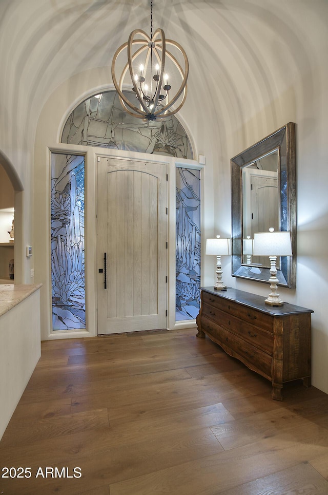 entrance foyer with hardwood / wood-style flooring, arched walkways, and an inviting chandelier