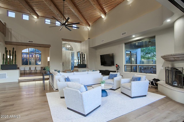 living area with visible vents, a fireplace with raised hearth, wood finished floors, and beamed ceiling