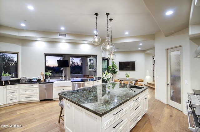 kitchen featuring light wood-style floors, open floor plan, white cabinets, and stainless steel dishwasher