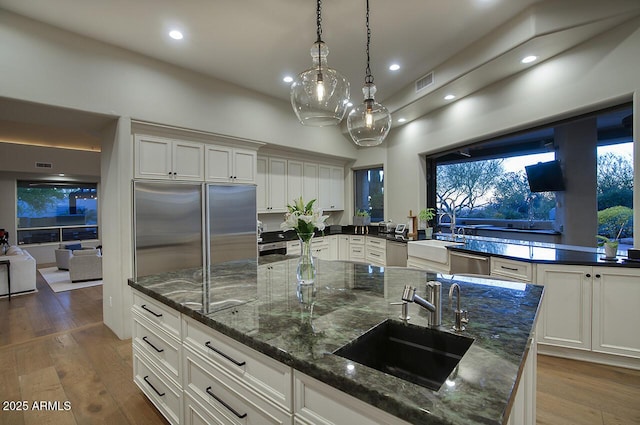 kitchen featuring visible vents, white cabinets, appliances with stainless steel finishes, hardwood / wood-style floors, and a sink