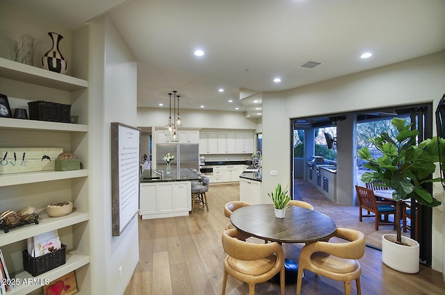 dining space with light wood-style flooring, built in shelves, visible vents, and recessed lighting