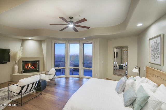 bedroom featuring recessed lighting, a glass covered fireplace, ceiling fan, wood finished floors, and access to outside