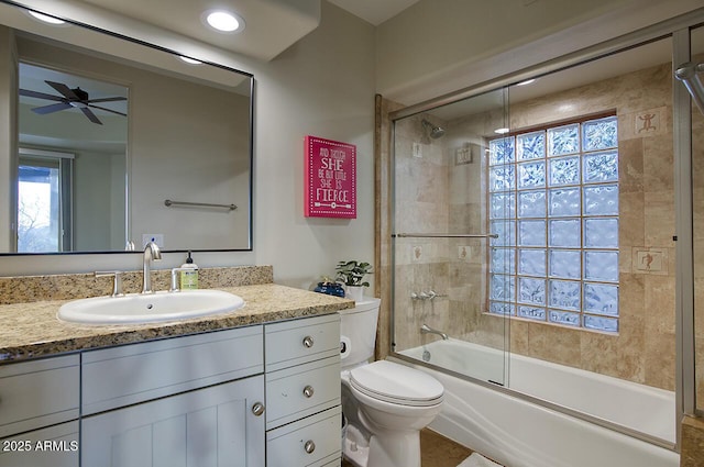 bathroom with toilet, ceiling fan, vanity, and enclosed tub / shower combo