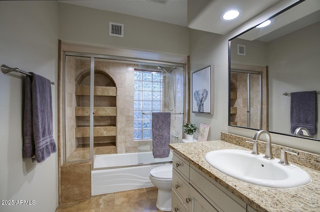 full bathroom featuring toilet, visible vents, bath / shower combo with glass door, and vanity