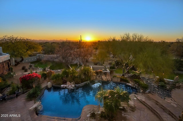 pool at dusk with fence and an outdoor pool