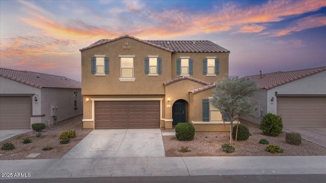 mediterranean / spanish-style home featuring concrete driveway, a tiled roof, an attached garage, and stucco siding