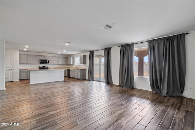 unfurnished living room featuring light wood-type flooring, a sink, visible vents, and recessed lighting