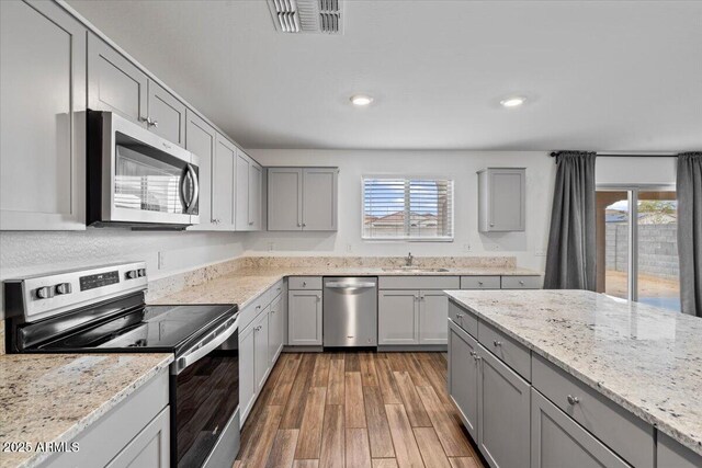 618 E Elm Ln, Avondale, AZ 85323 - kitchen with visible vents, light wood-style flooring, stainless steel appliances, gray cabinetry, and a sink