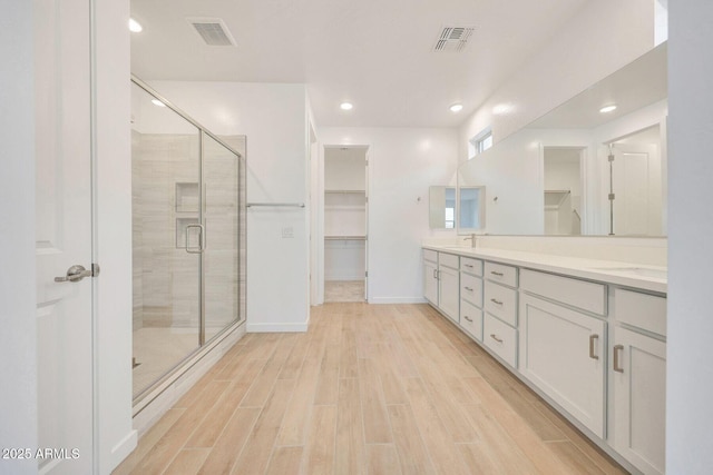 full bath featuring a stall shower, a spacious closet, visible vents, and wood tiled floor