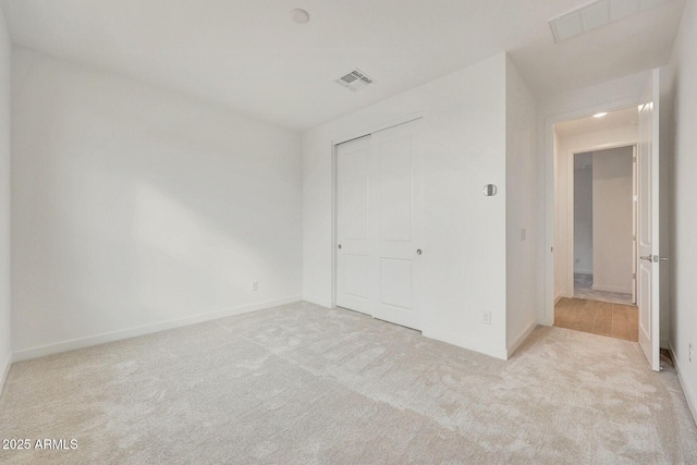 unfurnished bedroom with a closet, visible vents, baseboards, and carpet