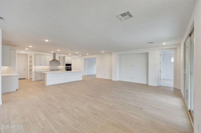 unfurnished living room with recessed lighting, visible vents, and light wood-type flooring