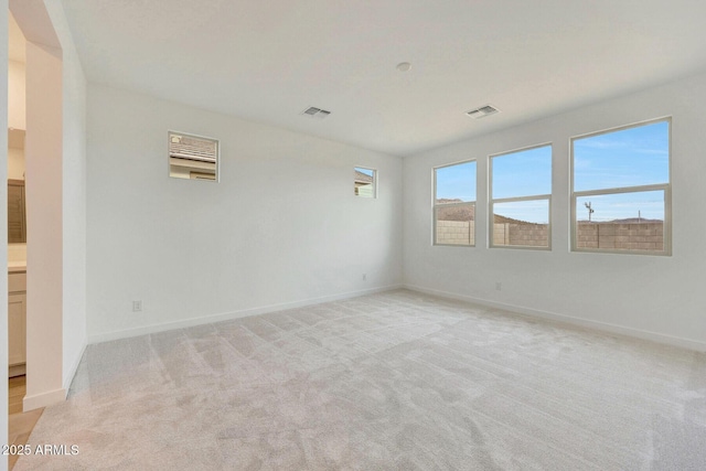 spare room featuring visible vents, light colored carpet, and baseboards