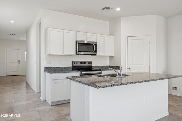 kitchen with visible vents, dark stone counters, appliances with stainless steel finishes, white cabinets, and a sink