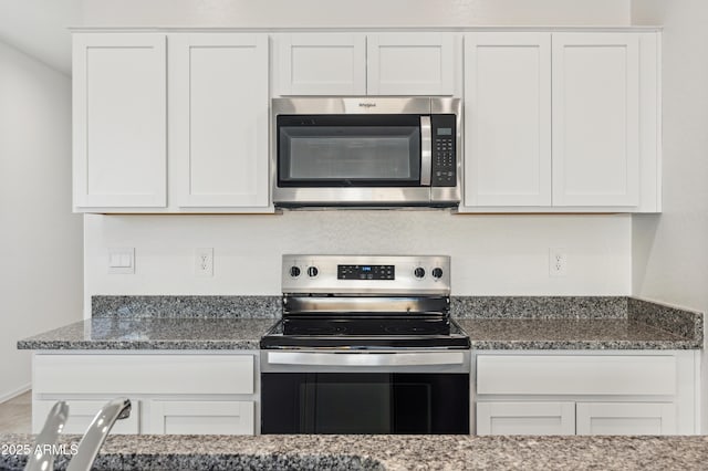 kitchen with white cabinets, appliances with stainless steel finishes, and dark stone countertops