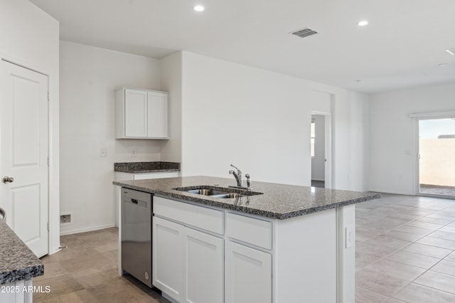 kitchen with visible vents, a sink, dark stone counters, stainless steel dishwasher, and a kitchen island with sink