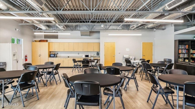 dining space featuring light wood finished floors, visible vents, and a towering ceiling