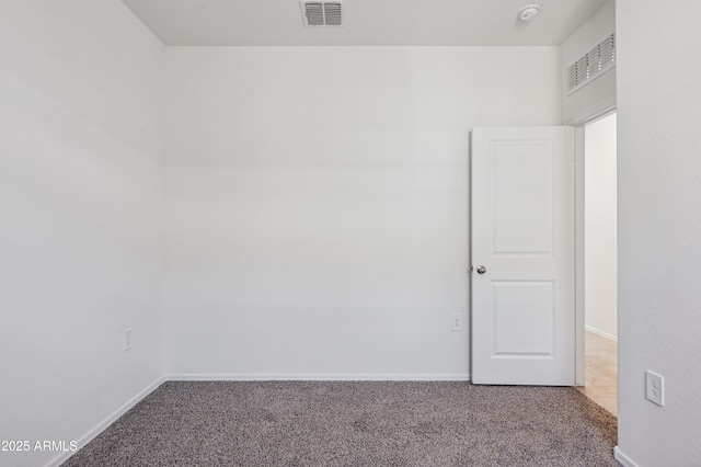 empty room featuring carpet, visible vents, and baseboards