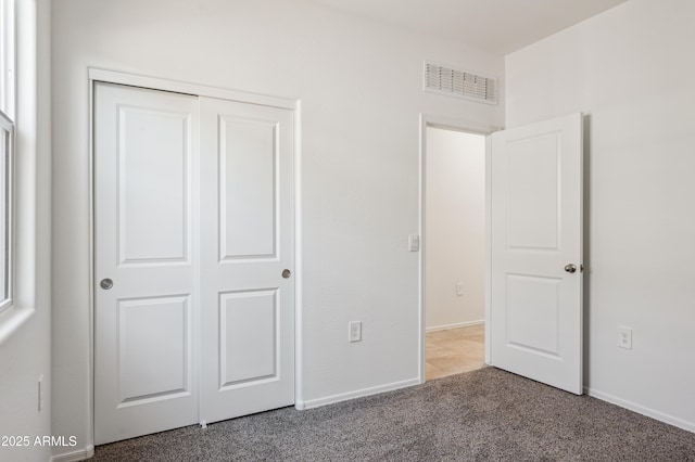 unfurnished bedroom featuring light colored carpet, visible vents, a closet, and baseboards