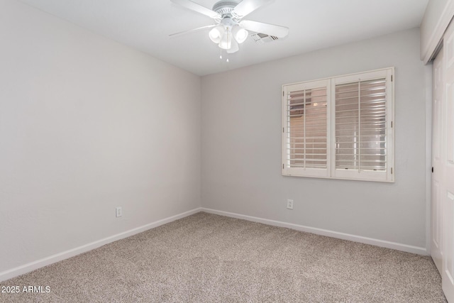carpeted empty room featuring baseboards, visible vents, and a ceiling fan