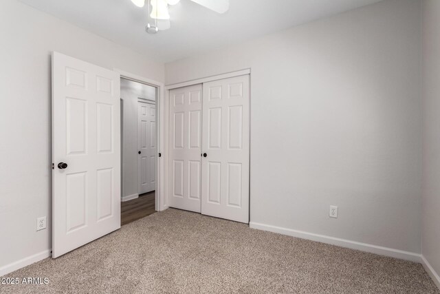 unfurnished bedroom featuring ceiling fan, a closet, baseboards, and light carpet