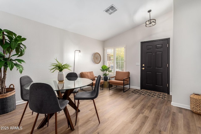 dining room featuring lofted ceiling, wood finished floors, visible vents, and baseboards