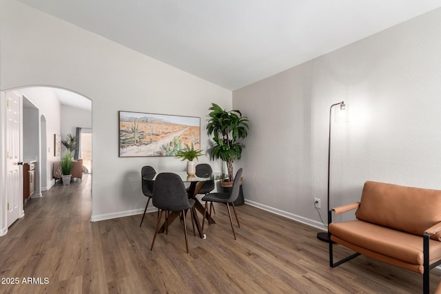 dining area with lofted ceiling, wood finished floors, baseboards, and arched walkways