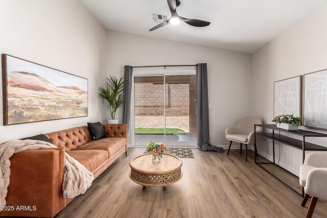 living area featuring wood finished floors, vaulted ceiling, ceiling fan, baseboards, and visible vents