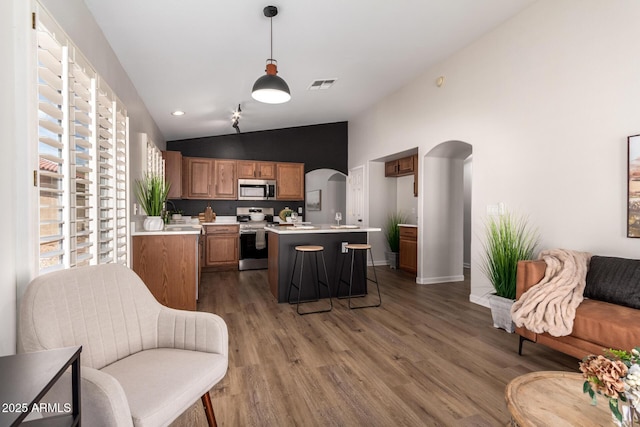 kitchen featuring lofted ceiling, appliances with stainless steel finishes, visible vents, light countertops, and arched walkways