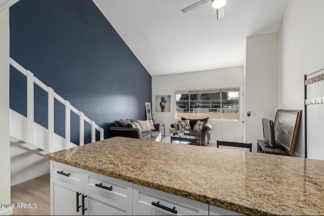 kitchen with light stone counters, wood-type flooring, white cabinets, and ceiling fan