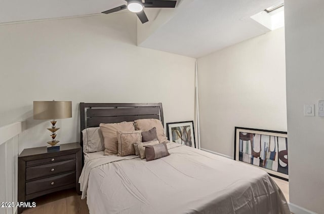 bedroom featuring ceiling fan, a skylight, and hardwood / wood-style floors