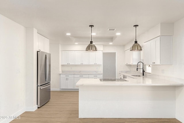 kitchen featuring sink, white cabinetry, hanging light fixtures, stainless steel refrigerator, and kitchen peninsula