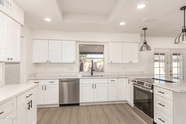 kitchen with stainless steel appliances, white cabinetry, hanging light fixtures, and sink