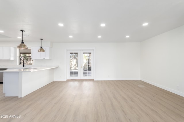 unfurnished living room featuring french doors, sink, and light hardwood / wood-style flooring