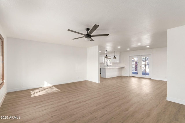 unfurnished living room with french doors, ceiling fan, hardwood / wood-style floors, and a textured ceiling