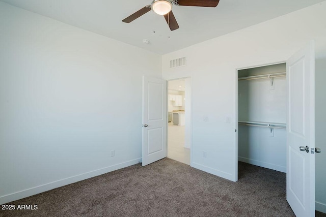 unfurnished bedroom with ceiling fan, a closet, and dark colored carpet