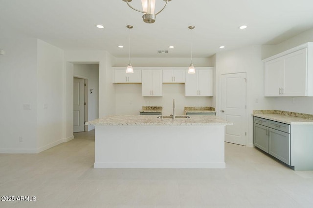 kitchen featuring sink, white cabinets, a center island with sink, and decorative light fixtures