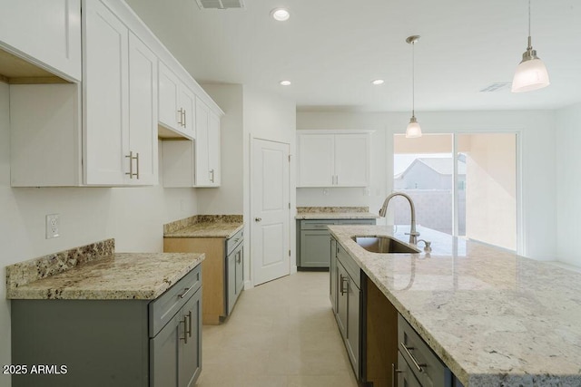 kitchen with sink, white cabinetry, pendant lighting, and a kitchen island with sink