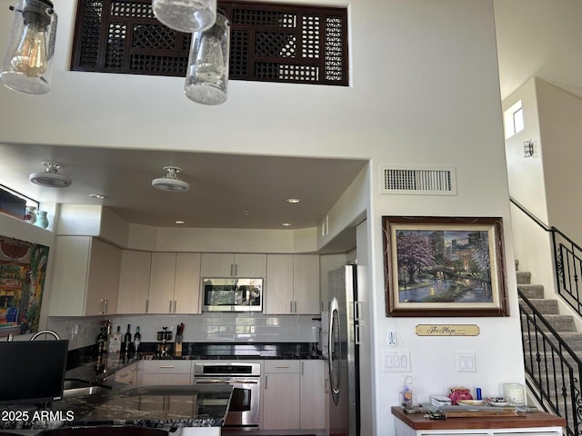 kitchen featuring backsplash, appliances with stainless steel finishes, kitchen peninsula, and dark stone countertops