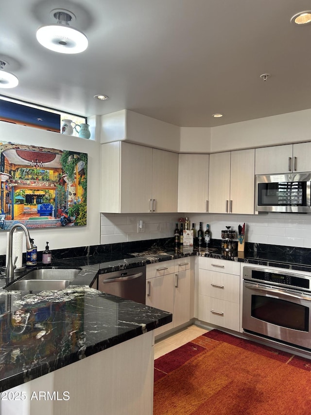 kitchen with stainless steel appliances, tasteful backsplash, sink, and dark stone countertops